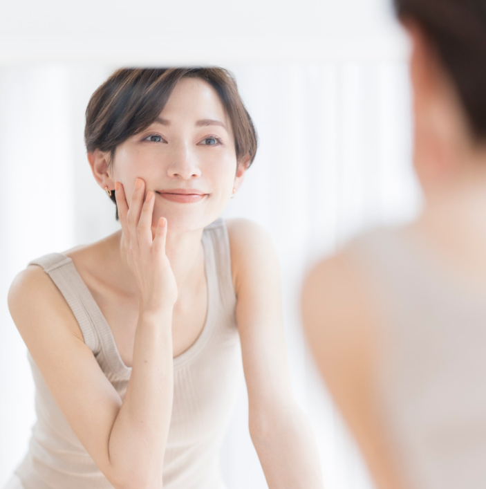 Woman applying Wonder Skin Restore Cream in front of a mirror, showcasing smooth skin and a polished appearance.