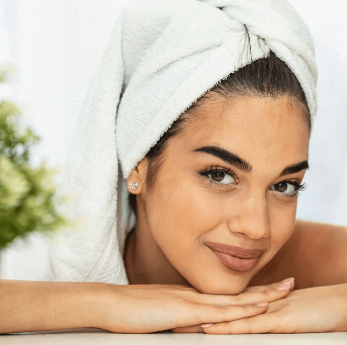 A woman with a towel on her head showcasing smooth skin, representing the Ultmate Cleansing Pen beauty tool in use.