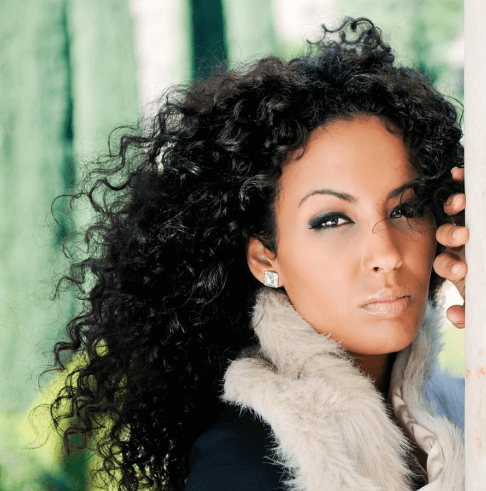 Model showcasing shiny, polished hair enhanced by Ultimate Hair Serum against a natural backdrop.