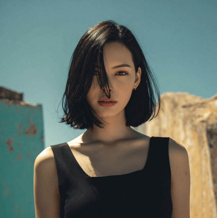Vital Renew Spray showcased on a model with sleek, shiny bob hairstyle outdoors, emphasizing polished hair appearance.