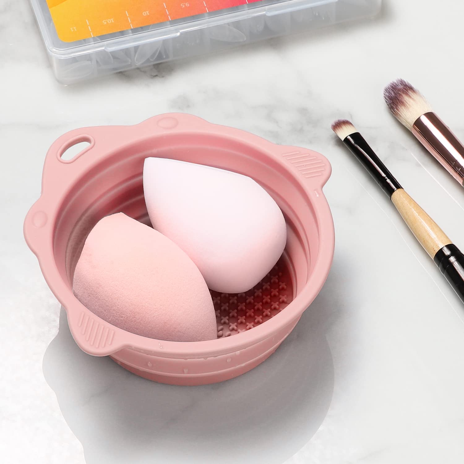 Quivy CleanBowl with makeup sponges in a pink silicone bowl on a marble surface.